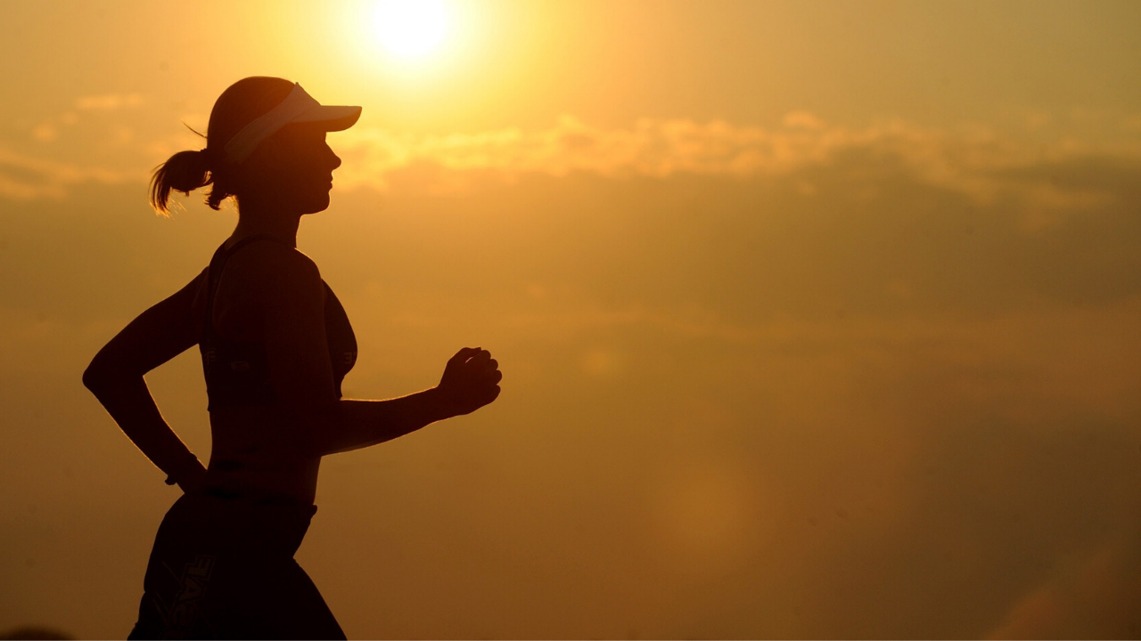 Better Breathing: Silhouette of a woman running set against a sunset background.